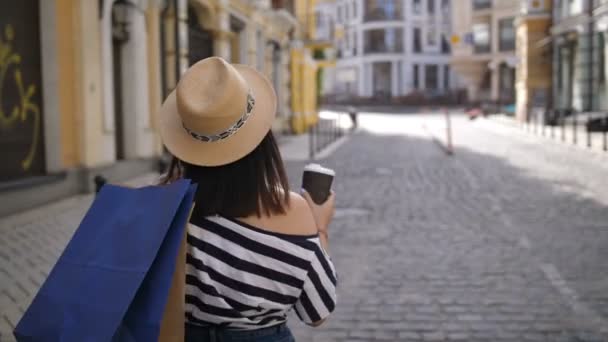 Menina asiática com sacos de compras andando ao longo da rua — Vídeo de Stock