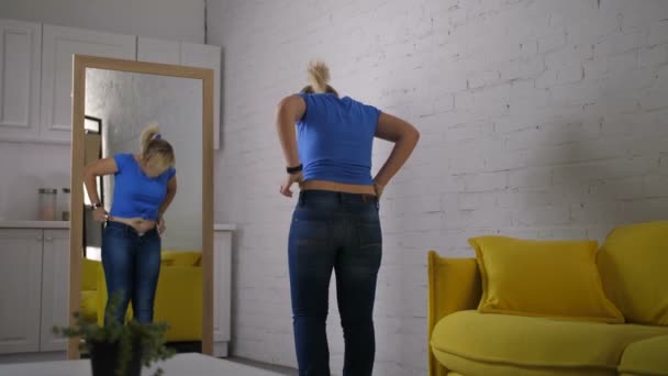 Nervózní žena se snaží tlačítko džíny s úsilím — Stock video