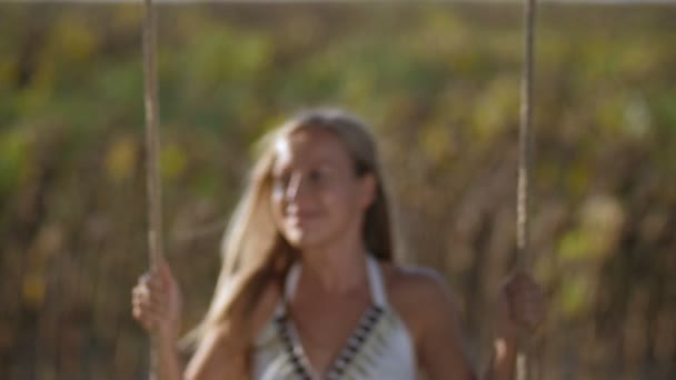 Радостная красивая женщина на качелях в солнечный летний день — стоковое видео