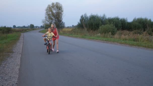 Schwester bringt ihrem kleinen Bruder Fahrradfahren bei — Stockvideo