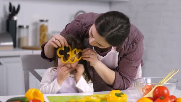 Мама и дочь веселятся, делая салат на кухне — стоковое видео
