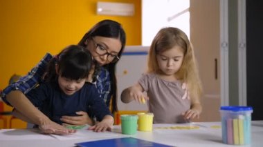 Resim dersinde öğretmen ile çeşitli çocuklar el