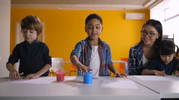 Diversos niños pintando a mano con acuarelas en clase — Vídeos de Stock
