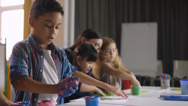 Lindos niños diversos pintando con las manos en la lección — Vídeo de stock