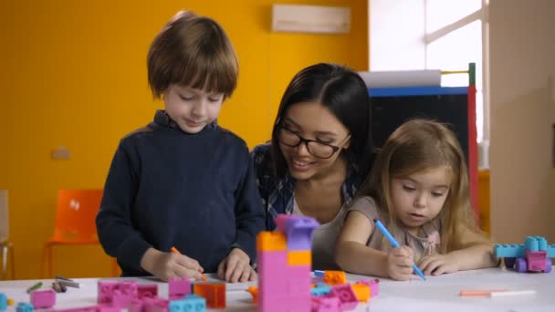 Leraar helpen klasse van preschool kinderen te trekken — Stockvideo