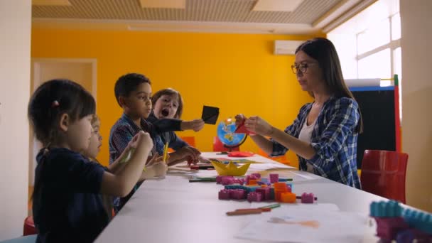 Разнообразные дети делают корабль из цветной бумаги — стоковое видео