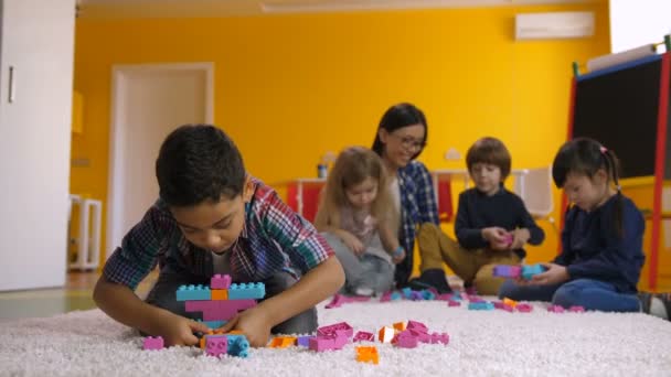 Positive Engrossed Mixed Race Boy Creating Colorful Construction Plastic Toy — Stock Video