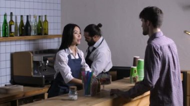 Güzel karışık yarış garson önlük kafe ve şık barista lezzetli kahve hazırlama erkek müşteriden sipariş almak. Sayaç barda içki siparişi alarak olumlu dostu kafe sahibi.