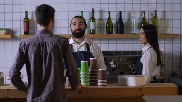 Varón barista comunicarse con el cliente en la cafetería — Vídeo de stock