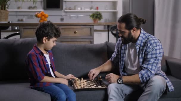 Inetelligent father teaching son to play chess — Stock Video