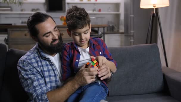 Pai amoroso ensinando filho para resolver cubo de quebra-cabeça — Vídeo de Stock