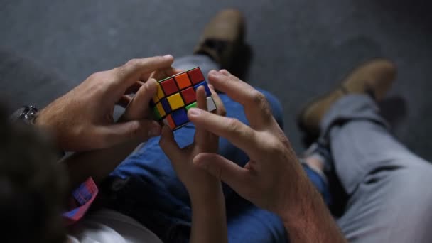 Hände des Jungen mit Hilfe von Papa sammeln Puzzle-Würfel — Stockvideo