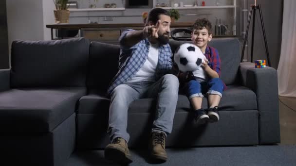 Aufgeregter Vater und Sohn schauen zu Hause Fußball im Fernsehen — Stockvideo