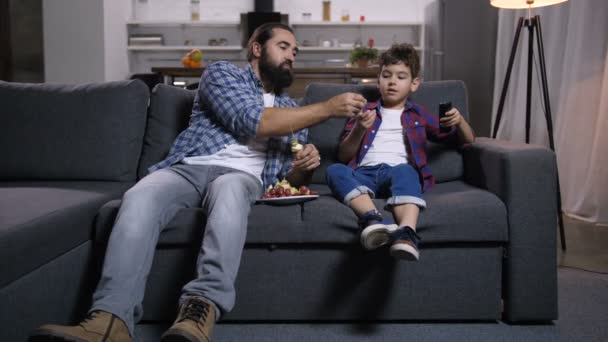 Père et fils détendus regardant un film à la télé — Video