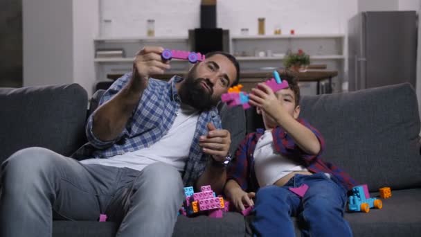 Возбужденные сын и папа наслаждаются развлечениями с игрушками — стоковое видео