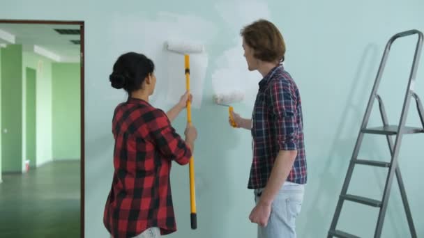 Пара прикрашає кімнату в новому домашньому розписі стіни — стокове відео