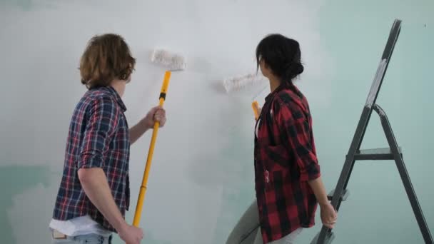 Excited carefree couple having fun painting wall — Stock Video