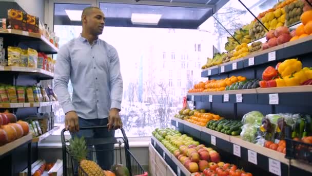 食料品店で製品を選択するトロリーを持つ男 — ストック動画