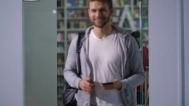 Çeşitli çokuluslu öğrenciler kütüphane okuduktan sonra bırakarak akıllı telefonlar ile meşgul. Hareket halindeyken cep telefonu tarama ders bitirme ve sınıf dışında yürüme pozitif çok etnik üniversite öğrencileri