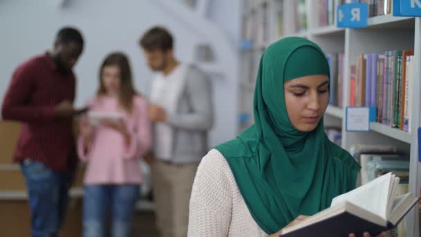 Μουσουλμανική φοιτήτριας διαβάζοντας ένα βιβλίο στη βιβλιοθήκη — Αρχείο Βίντεο