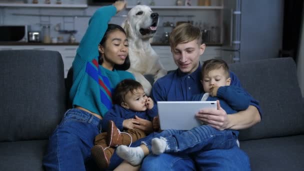 Vrouw kinderboerderij hond terwijl familie ontspannen op de sofa — Stockvideo