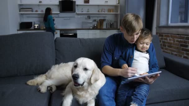 Far och barn pojke med hund limning på soffan — Stockvideo