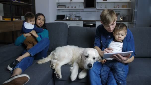 Familie sitzt auf Couch mit Haustier Labrador zu Hause — Stockvideo