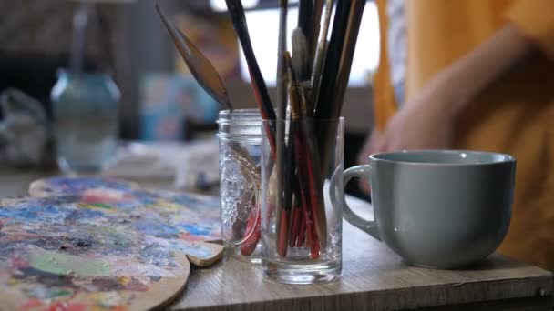 Ferramentas artísticas e xícara de bebida quente na mesa de trabalho — Vídeo de Stock