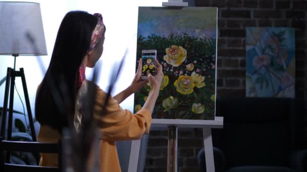 Kvinnliga målare fotografera konstverket med pioner — Stockvideo