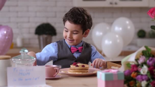 Закройте улыбающийся ребенок, украшающий блинчики для мамы — стоковое видео