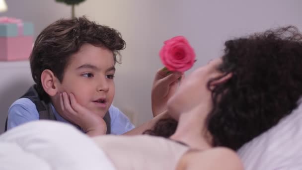 Niño acariciando durmiendo mamás cara con rosa — Vídeos de Stock