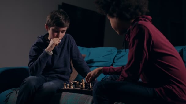 Різні друзі-підлітки грають в шахи вдома — стокове відео