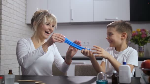 Счастливая мама с сыном, растягивающим слизь ручной работы — стоковое видео