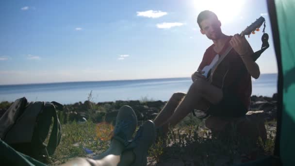 Preciosa pareja con guitarra disfrutando de la música en el campamento — Vídeos de Stock