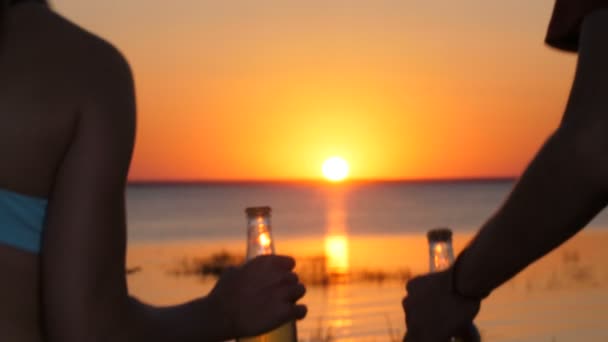 Casal com garrafa de cerveja andando na praia ao pôr do sol — Vídeo de Stock