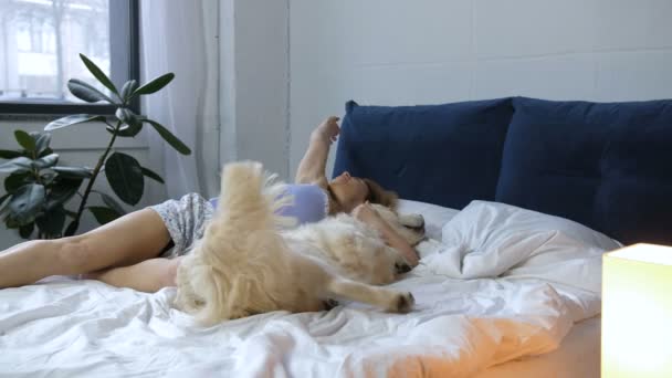 Feminino com cão retriever acordando no quarto — Vídeo de Stock
