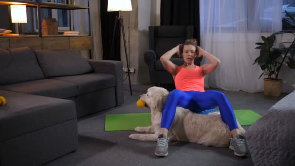 Sportliche Frau mit Hund macht Sit-Ups — Stockvideo