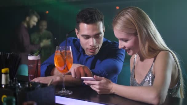 Pareja de citas usando teléfono sentado en el mostrador de bar — Vídeos de Stock