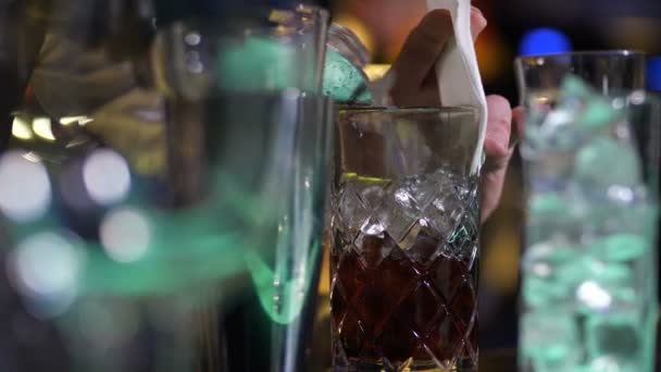 Смешивание стекла со льдом и спиртом стоя на баре — стоковое видео
