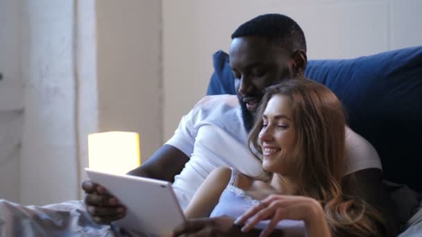 Pareja feliz abrazándose acostada en la cama con touchpad — Vídeos de Stock