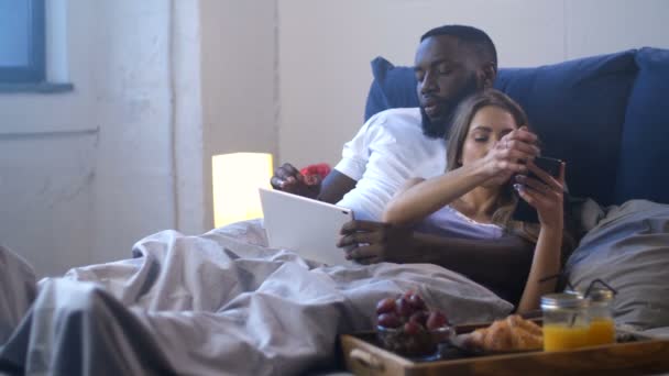 Пара використовує сучасні гаджети в ліжку — стокове відео