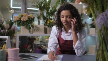 Çiçekçi çiçekçi de müşteri ile telefonda konuşurken Çiçekçi