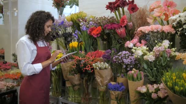 Blumenhändler prüft Preise mit Tablet im Blumenladen — Stockvideo