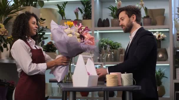 Ευτυχισμένος ανθοπώλης δίνοντας floral διευθέτηση στον πελάτη — Αρχείο Βίντεο