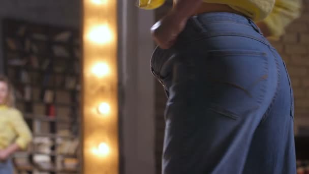 Vrouwelijk in oversized jeans genieten van slanke lichaamsvorm — Stockvideo
