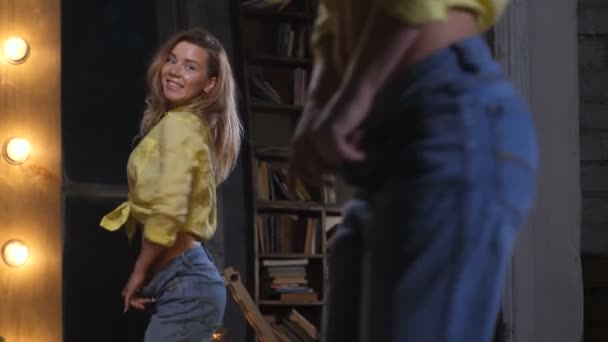 Vrolijke vrouw in grote jeans dansen op spiegel — Stockvideo