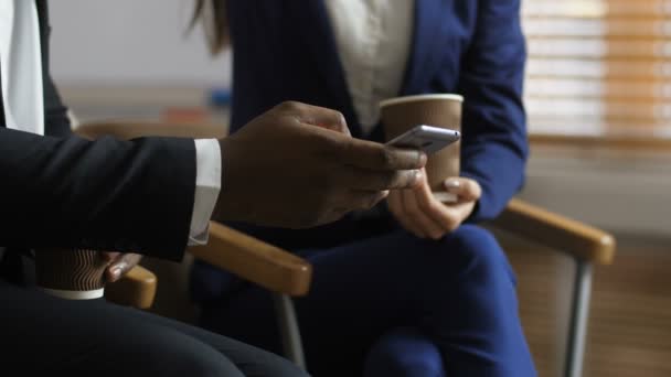 Midsectie van diverse collega's die op telefoon kijken — Stockvideo