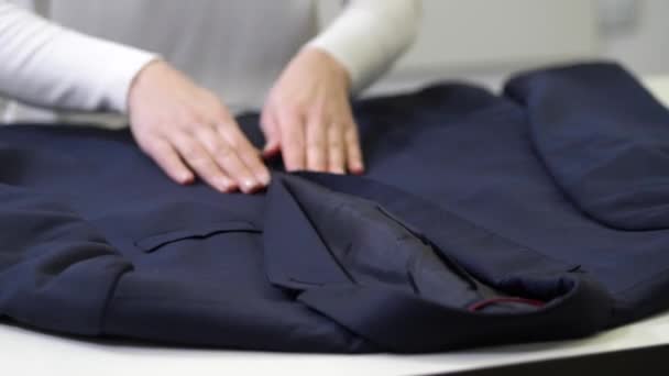 Руки працівника хімчистки оглядають куртку — стокове відео