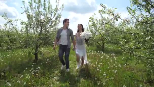 Feliz pareja corriendo de la mano en el jardín de frutas — Vídeos de Stock