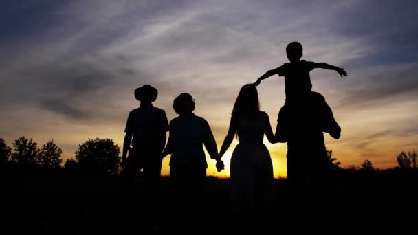 Три поколения семьи ходят на ярком закате — стоковое видео